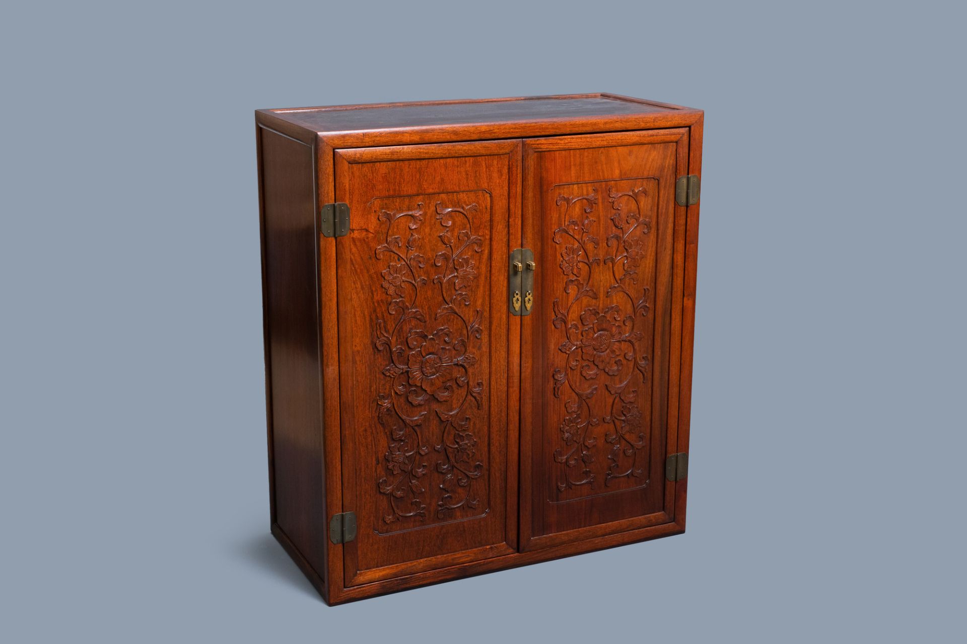 A Chinese wooden two-door cupboard with carved floral panels, 19th C.