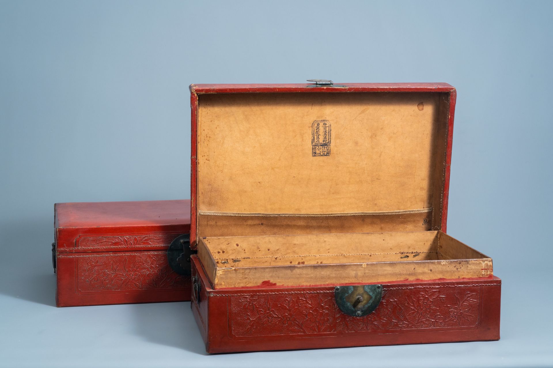 A pair of Chinese partly red lacquered leather travel trunks with floral design, 20th C