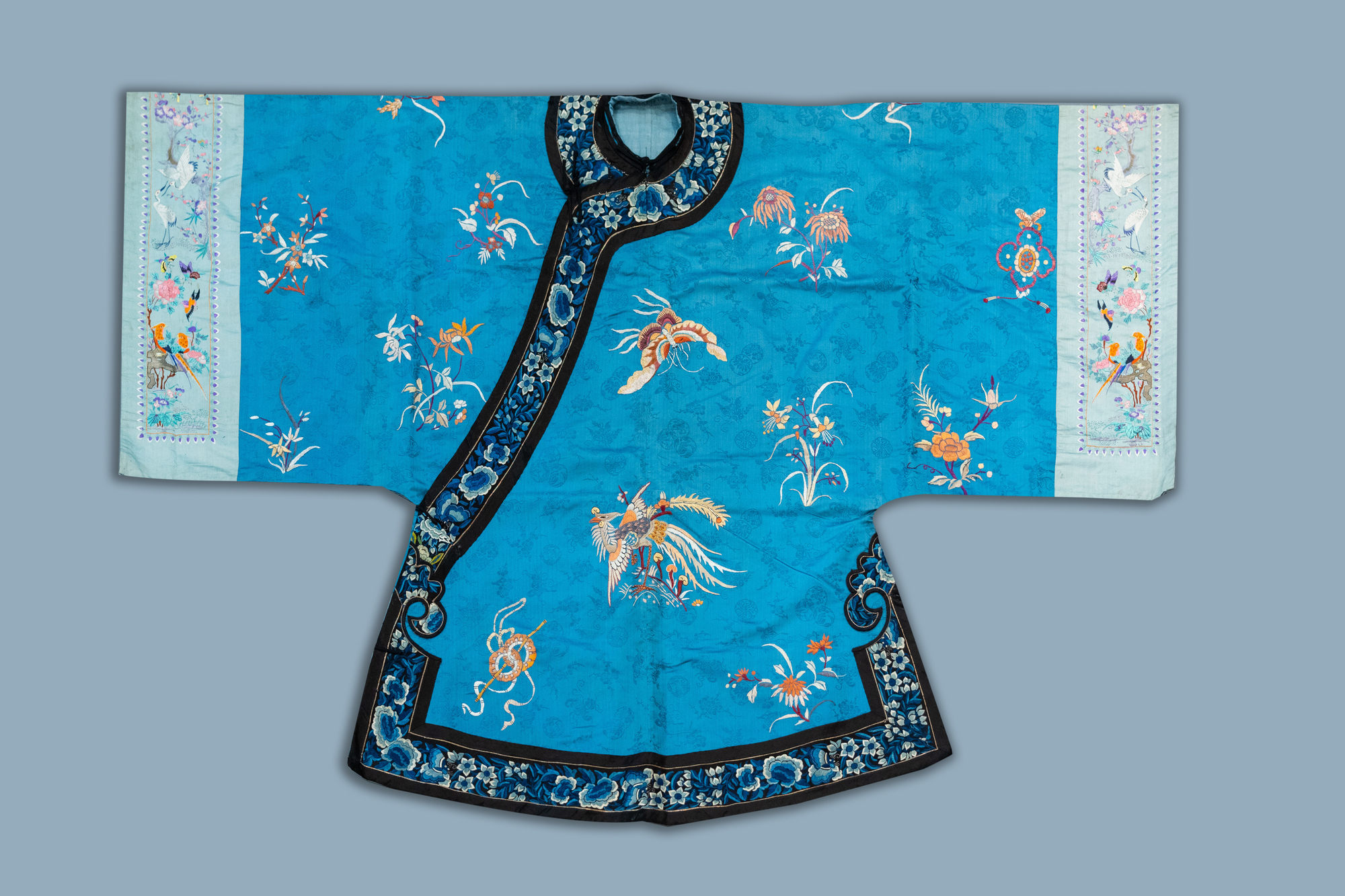 A Chinese blue ground embroidered silk women's robe with flowers and animals, 19th C.