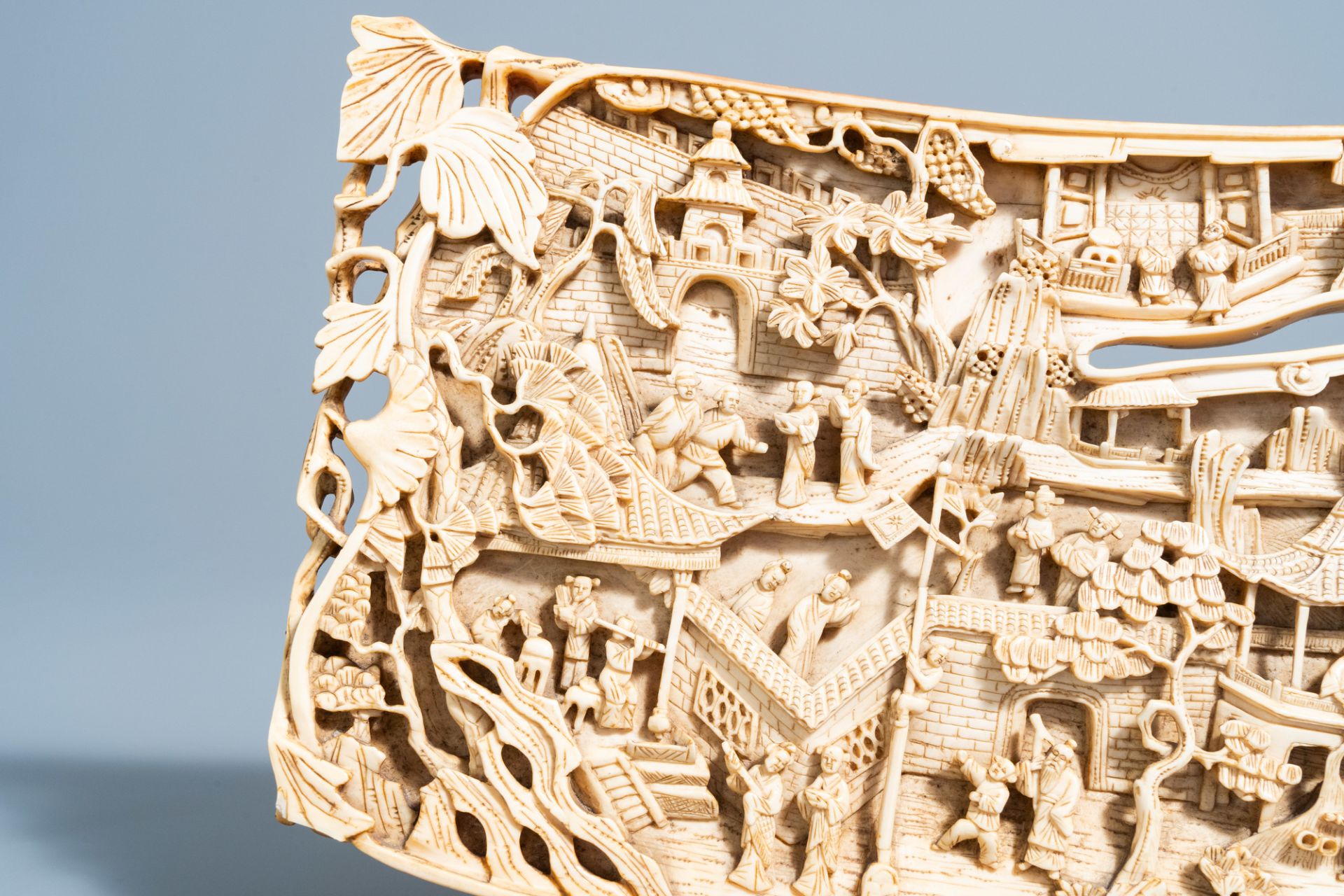 A Chinese richly carved ivory plaque with an animated city view on a wooden base, Canton, 19th C. - Image 10 of 15