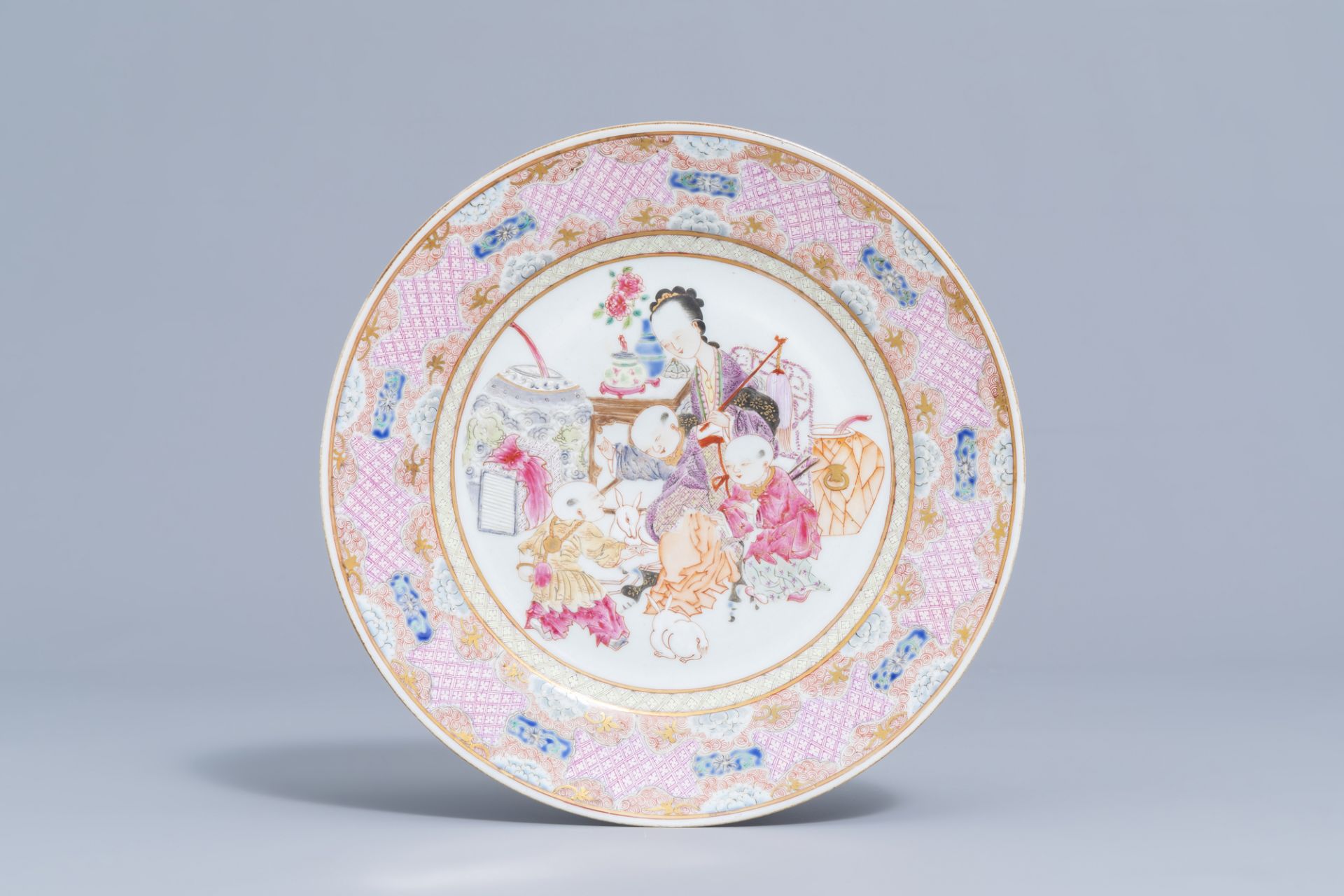 A Chinese famille rose Yongzheng style plate with figures and rabbits in an interior, 19th/20th C.