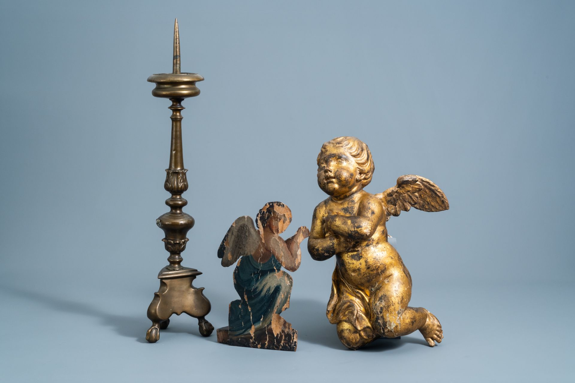 A patinated bronze pricket candlestick, a gilt wooden angel and a polychrome painted dummy board wit