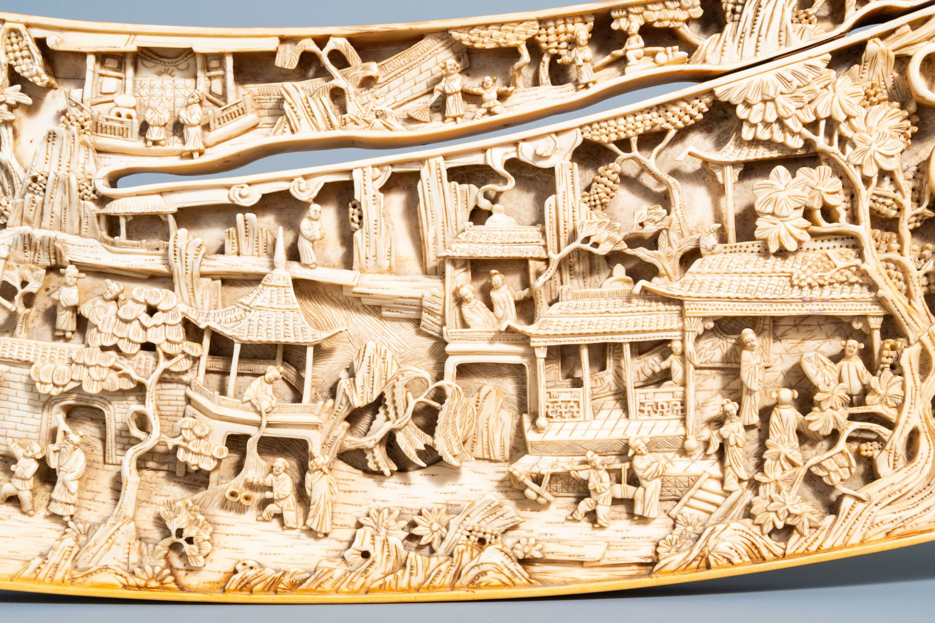 A Chinese richly carved ivory plaque with an animated city view on a wooden base, Canton, 19th C. - Image 12 of 15