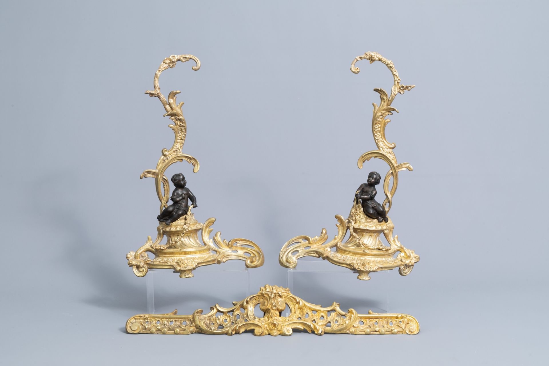 A pair of French Louis XV style patinated and gilt bronze andirons with putti, 19th C.