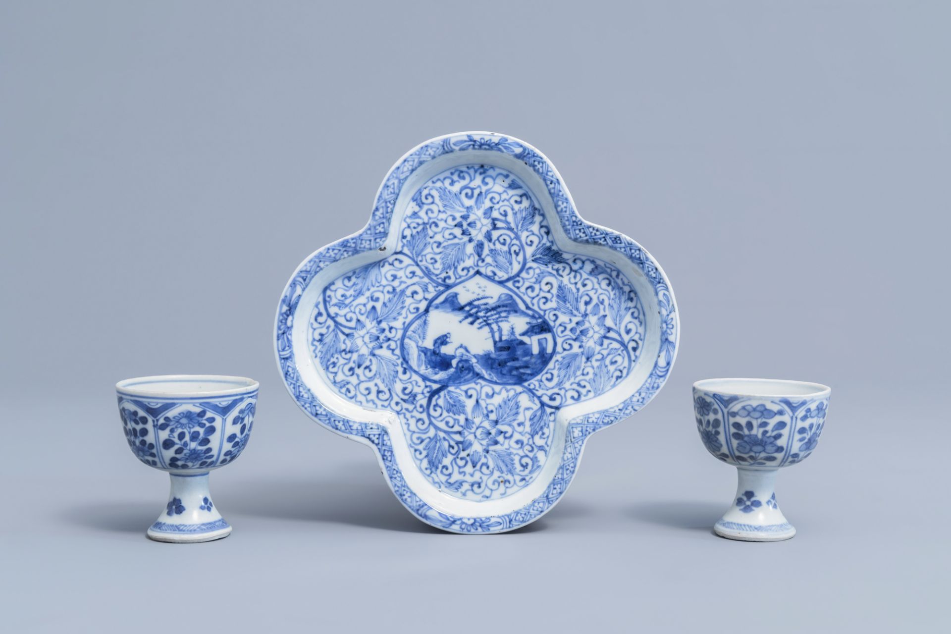 A pair of Chinese blue and white stem cups with floral design and a four-lobed teapot stand, Kangxi