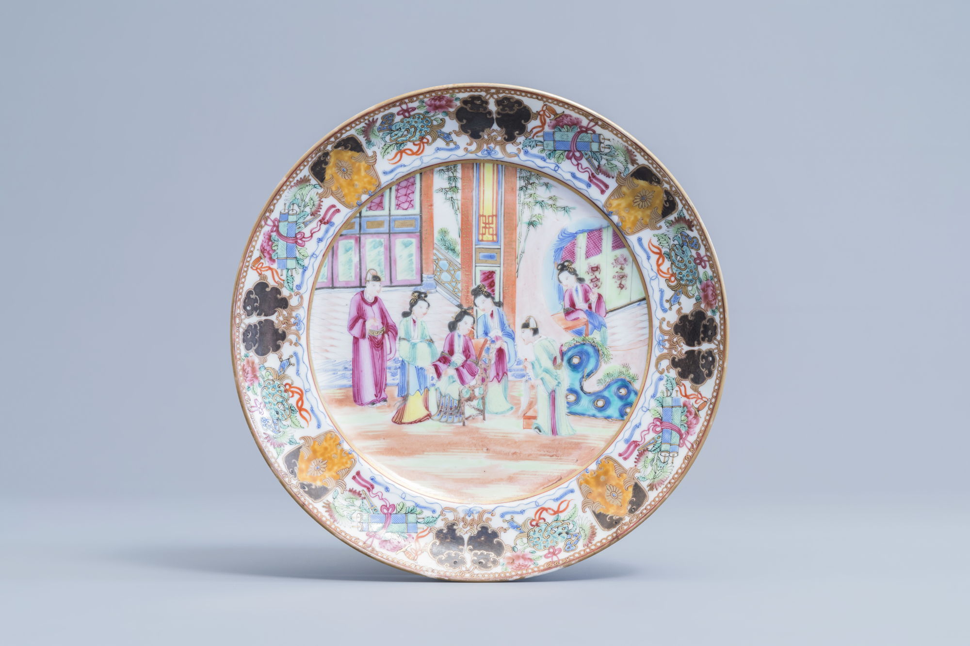 A Chinese Canton famille rose plate with a court scene and auspicious symbols, 19th C.