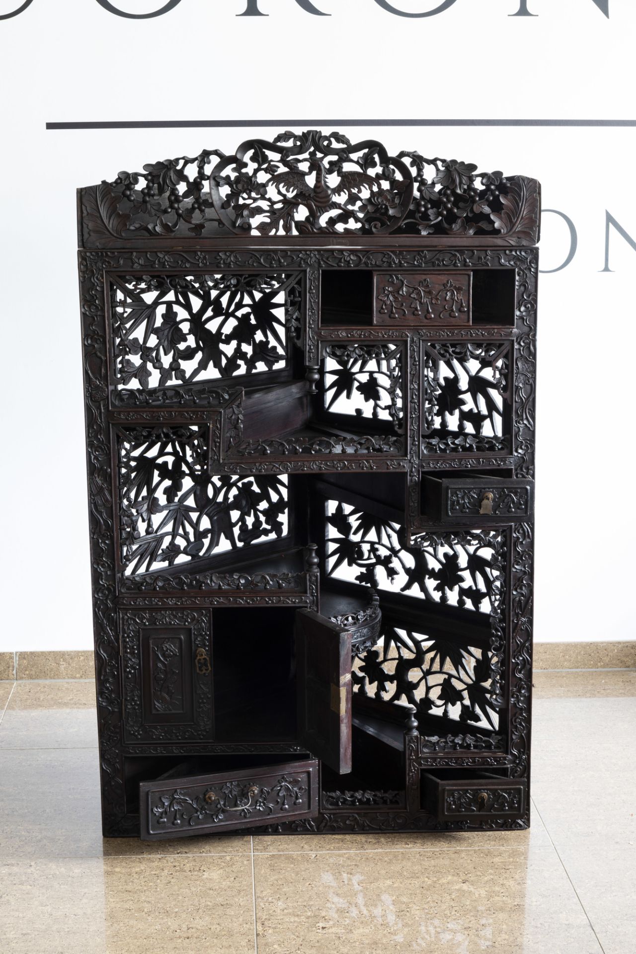 A Chinese carved wooden open worked corner display cabinet with floral design, 19th/20th C. - Image 3 of 7