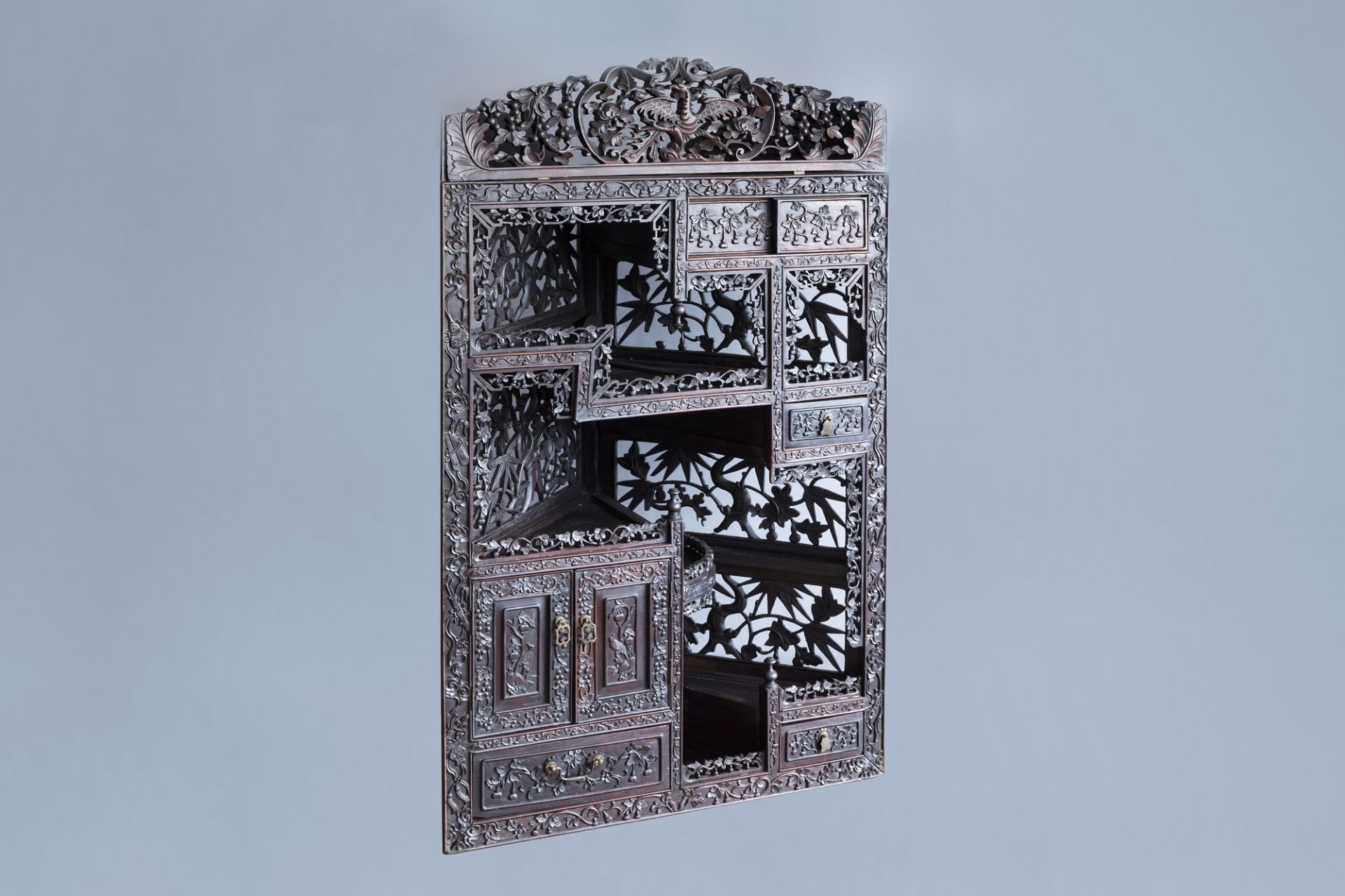 A Chinese carved wooden open worked corner display cabinet with floral design, 19th/20th C.