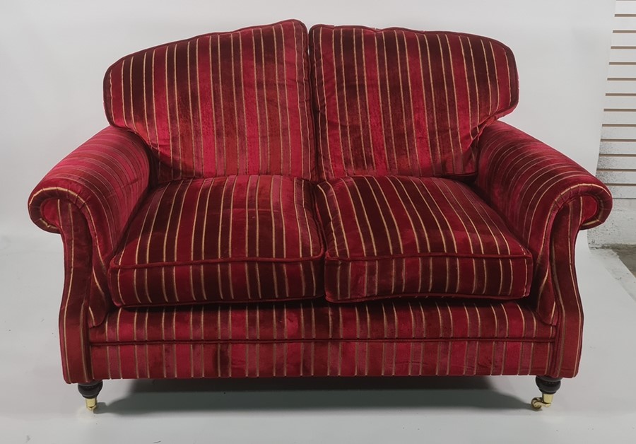 Pair of two-seater modern sofas in a burgundy ground striped upholstery, on turned supports to brass