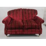 Pair of two-seater modern sofas in a burgundy ground striped upholstery, on turned supports to brass