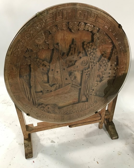 Modern Eastern circular table with carved top featuring figures in boat in landscape and one further - Image 2 of 2