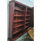 Large stained pine open bookcase, the moulded cornice above assorted shelves, on squat bracket feet,