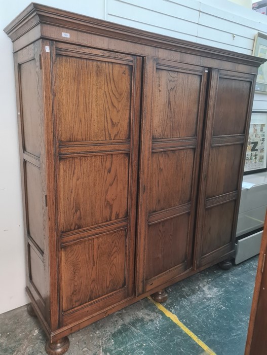 20th century oak three-door wardrobe with cavetto moulded cornice above the panelled doors, with