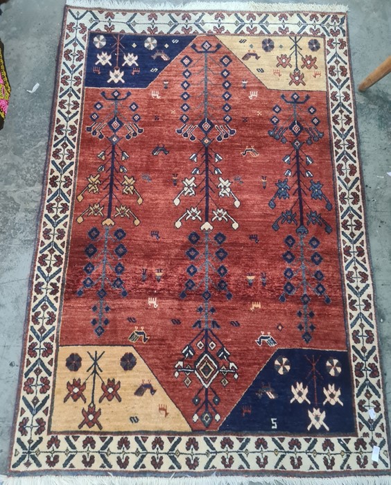 Contemporary Eastern wool rug with brick red field, decorated with stylised flowering plants, blue