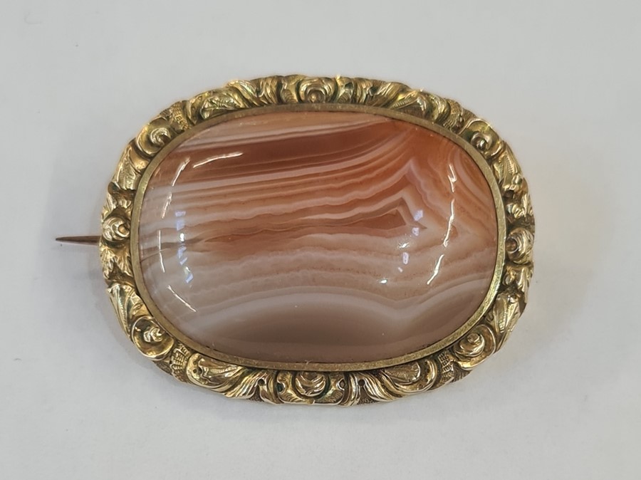 Early Victorian gilt metal brooch set with a central cabochon agate within a chased floral border,