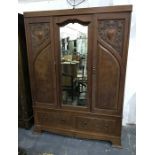 Early 20th century oak wardrobe, the central mirrored section flanked by cupboard doors, on base