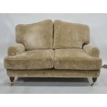 Two-seat Laura Ashley sofa in pale gold coloured upholstery, turned supports to brass caps and