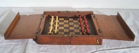 A travel chess board, with one set of pieces stained red, one white, 20.2cm