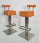 Pair of modern breakfast bar stools covered in orange, on chrome-style bases  80 cms h.  they dont