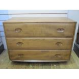 Ercol chest of three long drawers, on plinth base, with circular wooden handles (one missing),