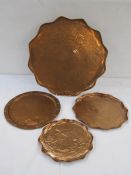 Newlyn style circular copper tray with wavy edge, floral and bud engraved, two similar smaller trays