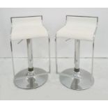 Pair of adjustable chrome stools on circular chrome bases, with chrome foot rests and white