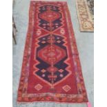 Large red ground Iranian runner, multi-coloured unique medallion design, 330 x 120cm