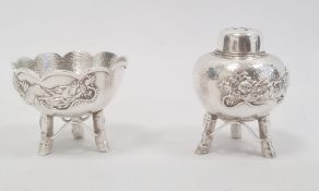 A silver pepperette and matching salt, Chinese decorated with dragon in relief on a hammered ground,