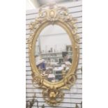 Decorative gilt girandole wall mirror of oval form with laurel leaf border, surmounted by floral