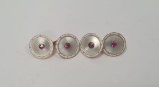 Pair of 15ct gold and ruby set cufflinks, the circular mother-of-pearl linked discs set within white