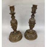 A pair of Indian/Burmese white coloured metal candlesticks, relief of warriors/hunters and