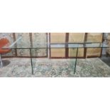 Plate glass and metal dining table, the two upright glass trestle legs united by a central metal