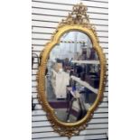 Decorative gilt wall mirror of shaped oval form, with a foliate scrolling outer border, 82cm wide