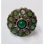 A silver coloured metal and emerald ring, possible Indian, circular/flower shaped with central