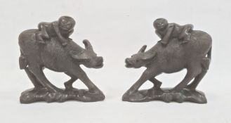 Pair of carved hardwood models of boys riding buffalo, each 12cm high approx. (2)