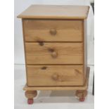 Modern pine bedside table fitted with three short drawers, on bun feet and plastic castors, 44cm