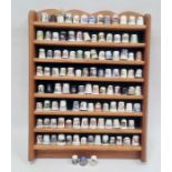 Collection of thimbles on a wooden hanging display shelf including examples by Spode, Wyeside,