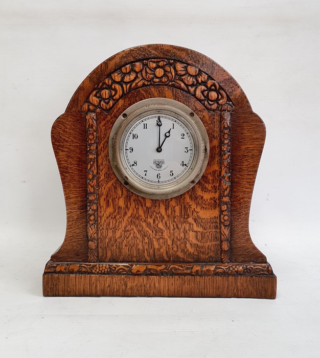 Mid 20th century Smiths oak timepiece, the arched case stylised flowerhead carved on plinth base,