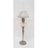 Brass and glass oil lamp having cut well, glass panelled shade, on brass mask and tapering column,