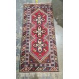 Modern Eastern-style rug, red ground with three central interlinked medallions, in creams, browns,