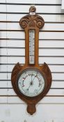 Oak aneroid barometer with scroll pediment, the enamel dial with thermometer, 82cm long overall