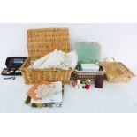 Wicker picnic basket filled with assorted linens and textiles, table ware, another basket, a