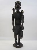 Large African carving of man with spear, wearing hat and carrying kill, 70cm high approx.