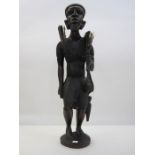 Large African carving of man with spear, wearing hat and carrying kill, 70cm high approx.