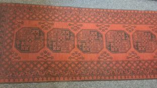 Modern Eastern-style red ground runner with repeating central medallions in reds and blacks, 387cm x