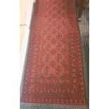 Modern red ground rug with repeating central medallions, in reds, blacks and whites, 296cm x 80cm
