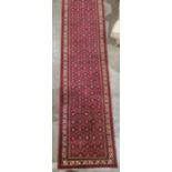Large modern Eastern-style red ground runner with stepped border, 484cm x 78cm