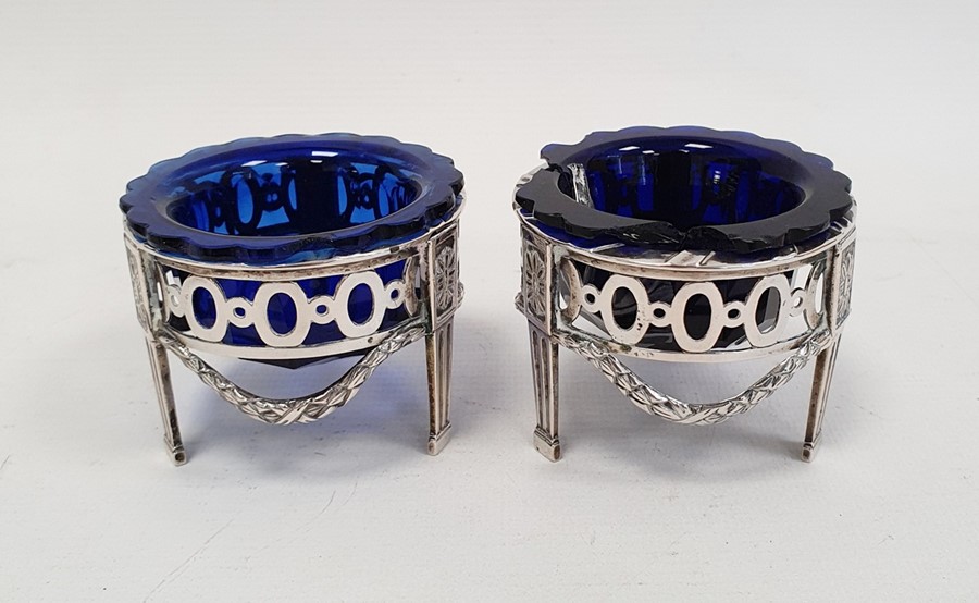 A pair of early 20th century silver coloured metal salts with blue glass liners, pierced