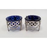 A pair of early 20th century silver coloured metal salts with blue glass liners, pierced