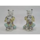 Pair of Chinese porcelain seated figures, laughing boys, each holding a blue and white vase, 16cm